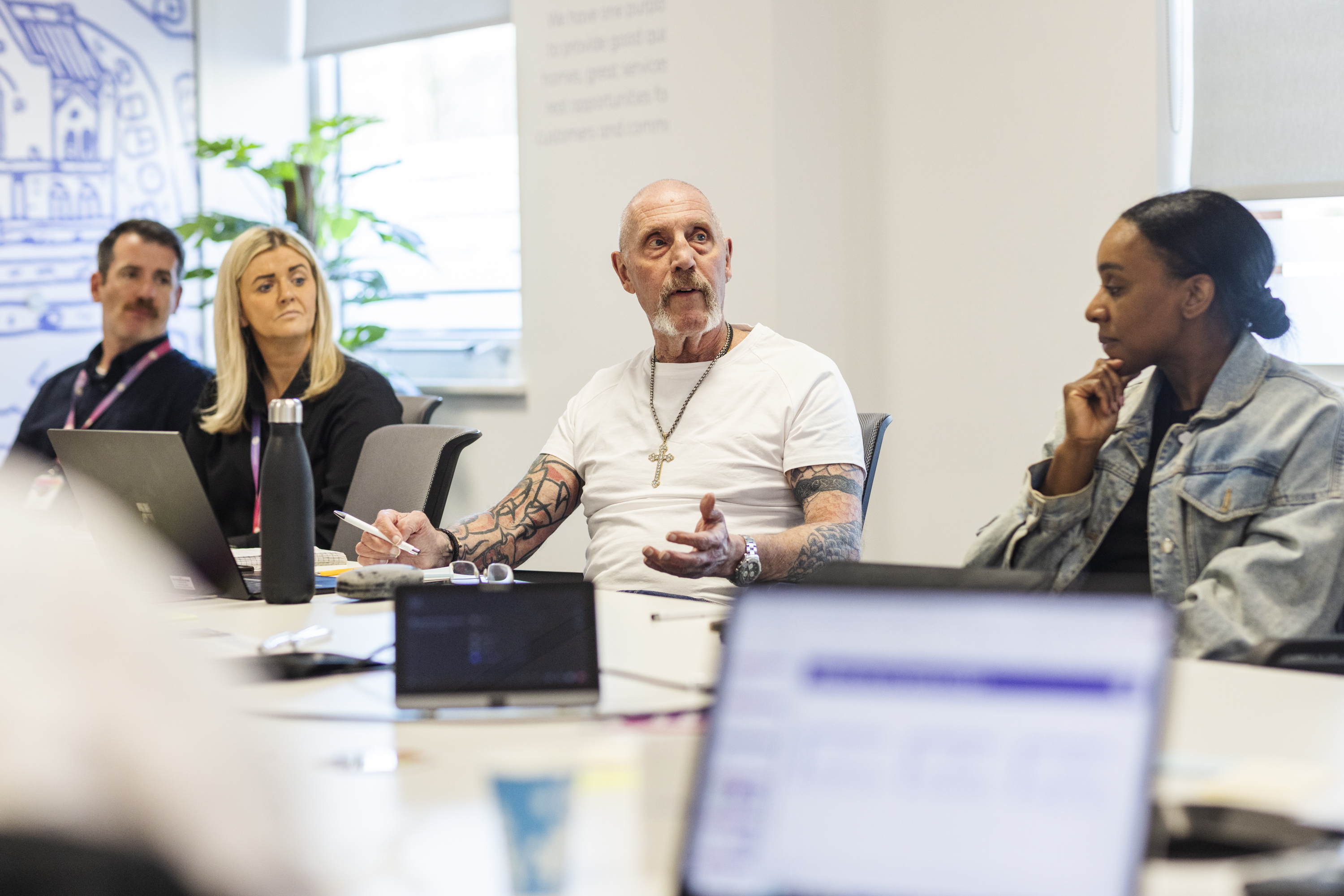 One Manchester Colleague in discussion at a table with other people.