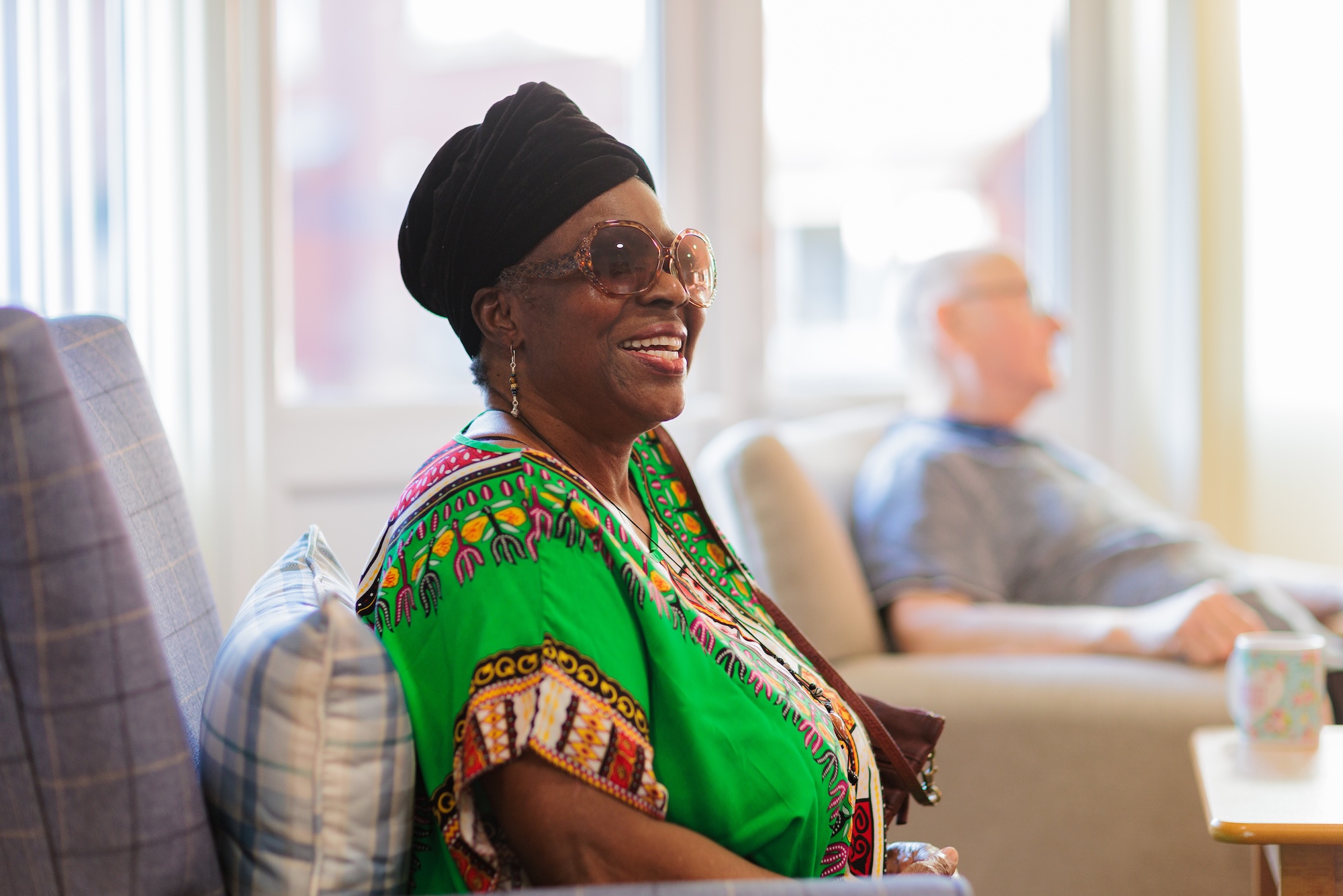 Woman sat in a chair smiling wearing a green dress. 