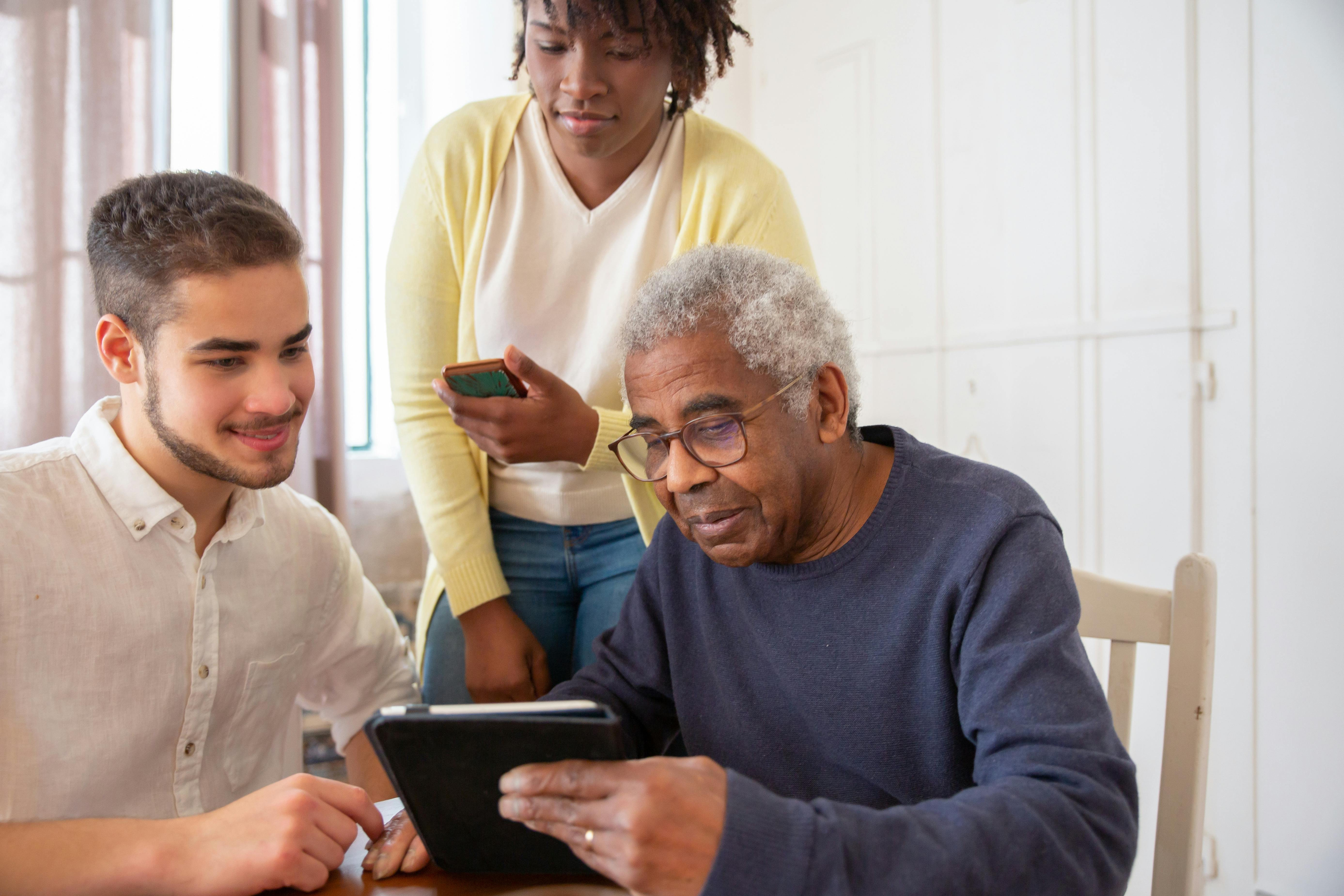 Two people helping a person with a tablet