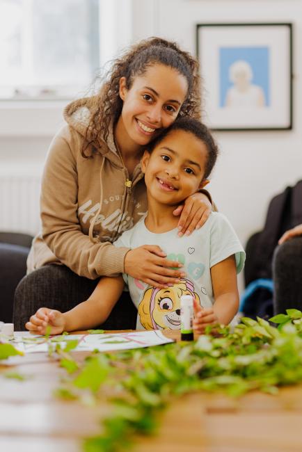 A mother and child sat down having their photograph taken at a table
