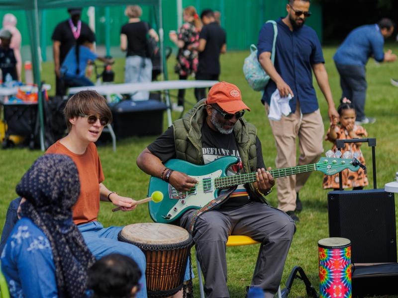 customers of all ages playing guitar and drums outside together