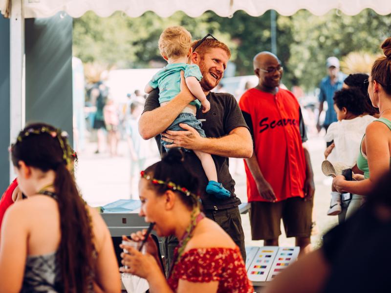 An image of a customer holding a child at a community event