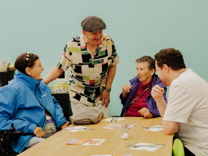 A group of four older people sat together chatting and laughing