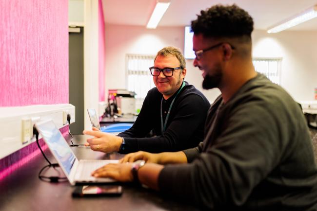 2 men sat at computer working together in The Work Shop in Moss Side