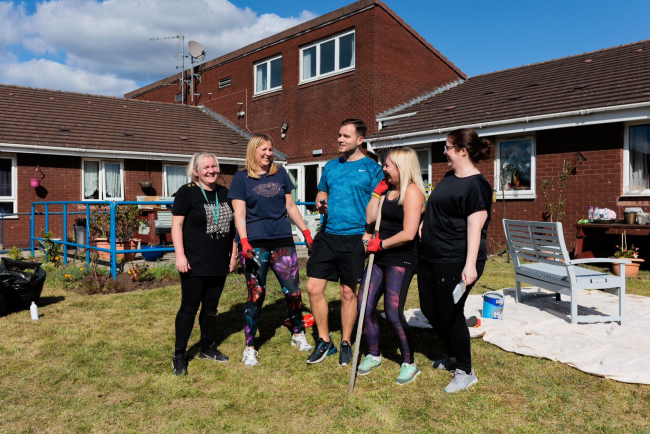 A picture containing volunteers standing in a garden. 