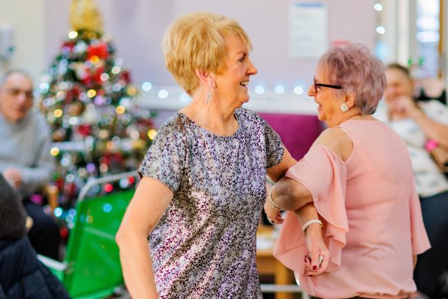 Two ladies dancing arm in arm at an ILS Christmas party