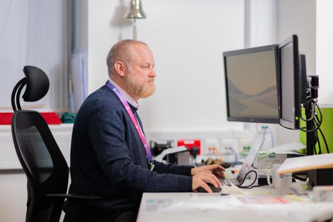 A photo of a man in an office working on IT equipment