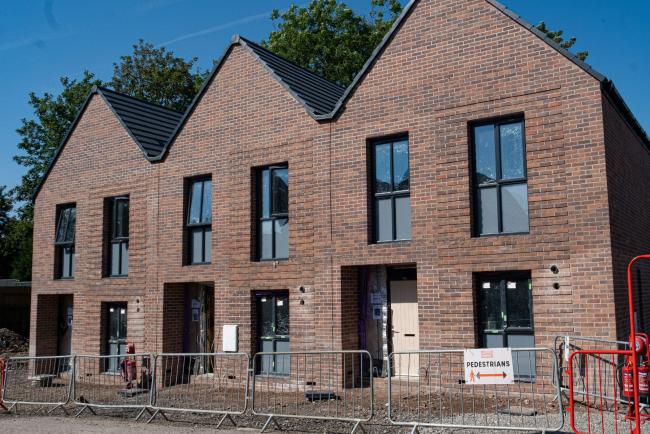 A picture containing a construction site with 3 houses being built in Moston. 