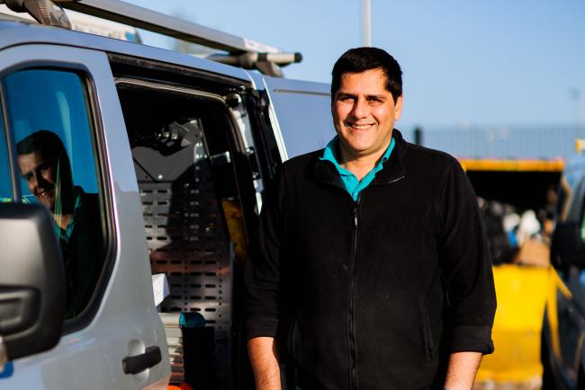 An image of a male One Manchester colleague smiling stood next to a work van